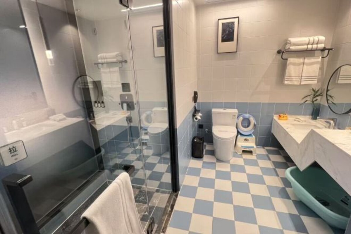 A bathroom with a checkered floor, a glass shower enclosure, a toilet, a bidet, and a sink with a towel rack.