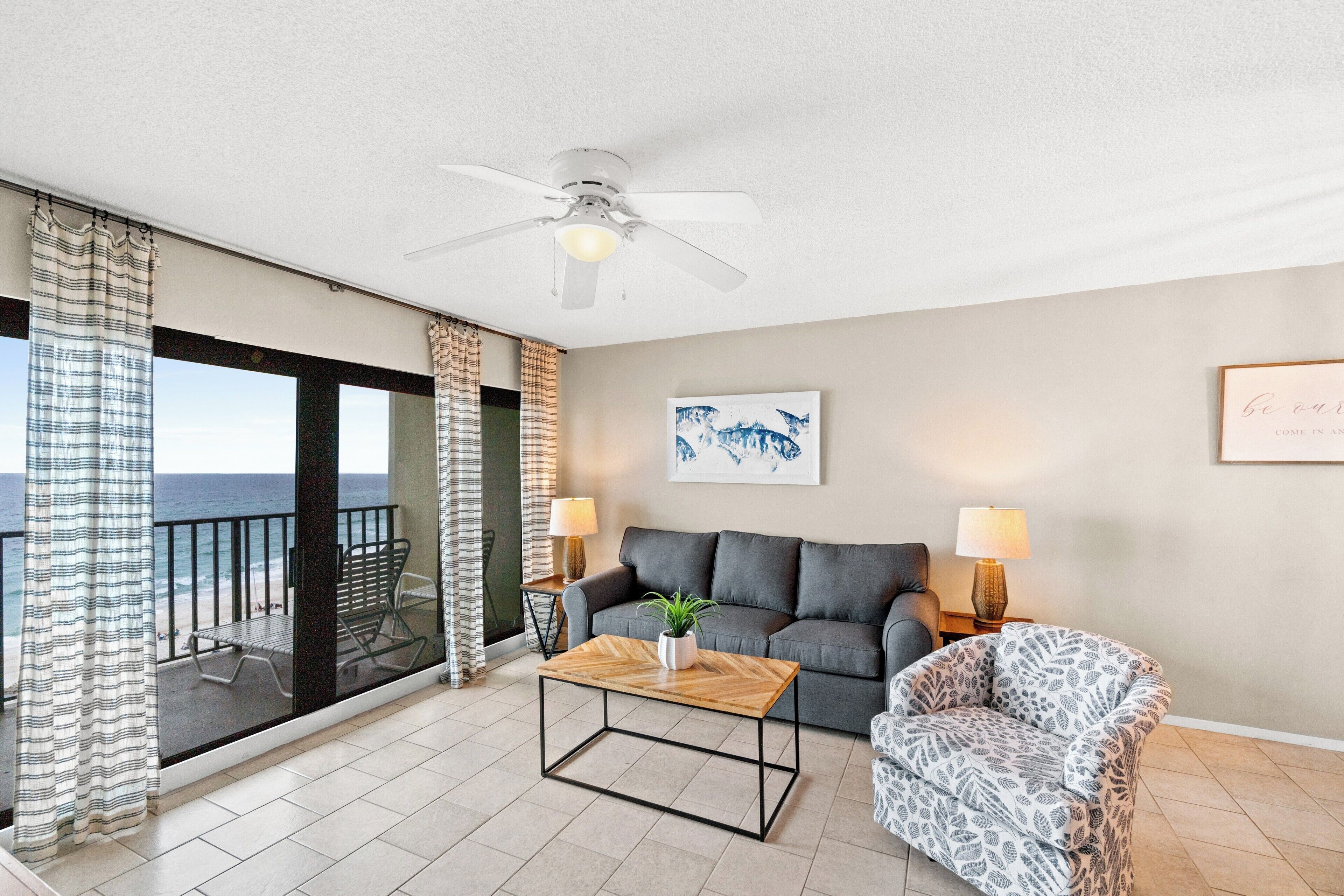 A living room with a sofa, armchair, coffee table, and a ceiling fan.