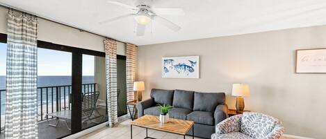 A living room with a sofa, armchair, coffee table, and a ceiling fan.