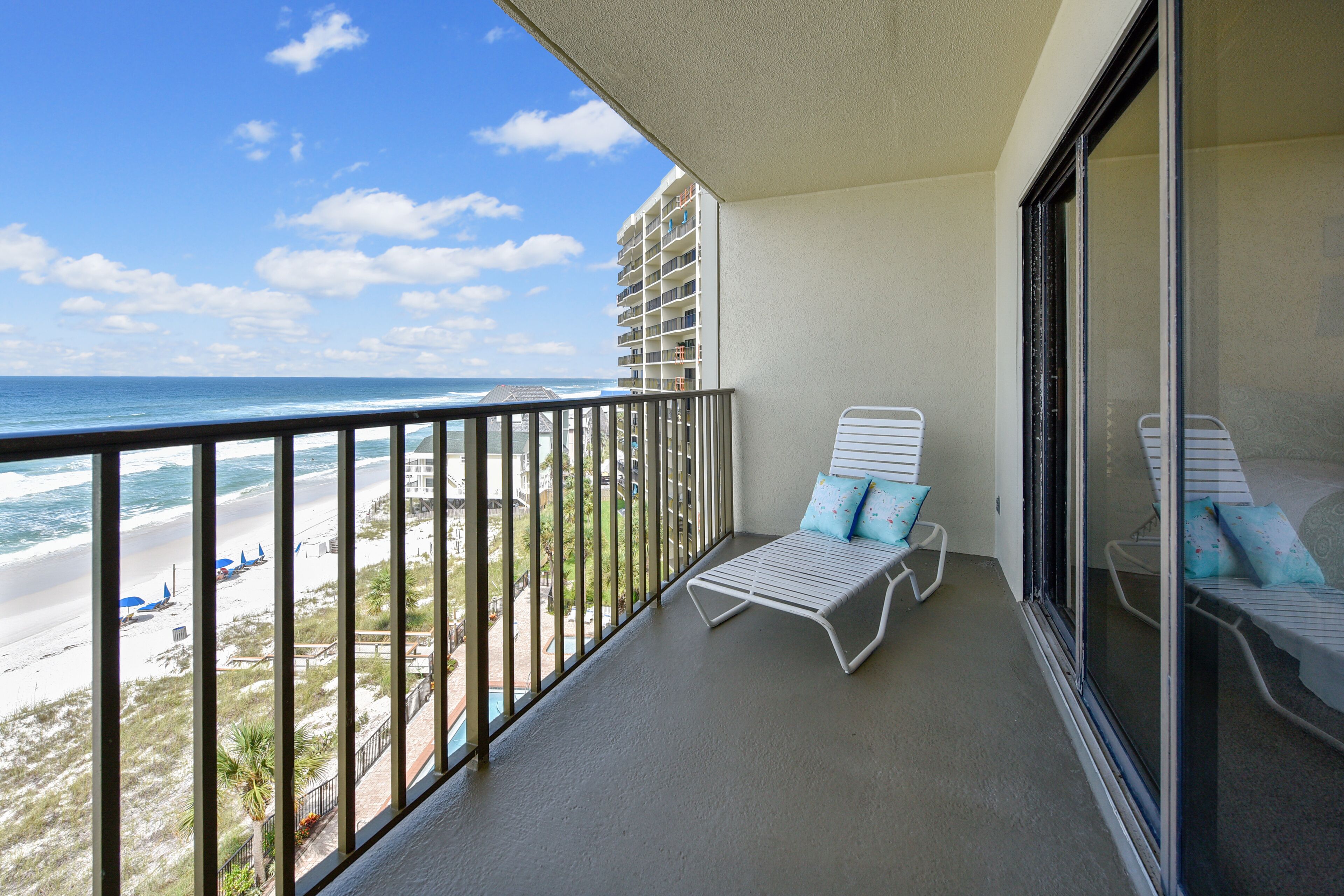 A balcony with a view of the beach and ocean.