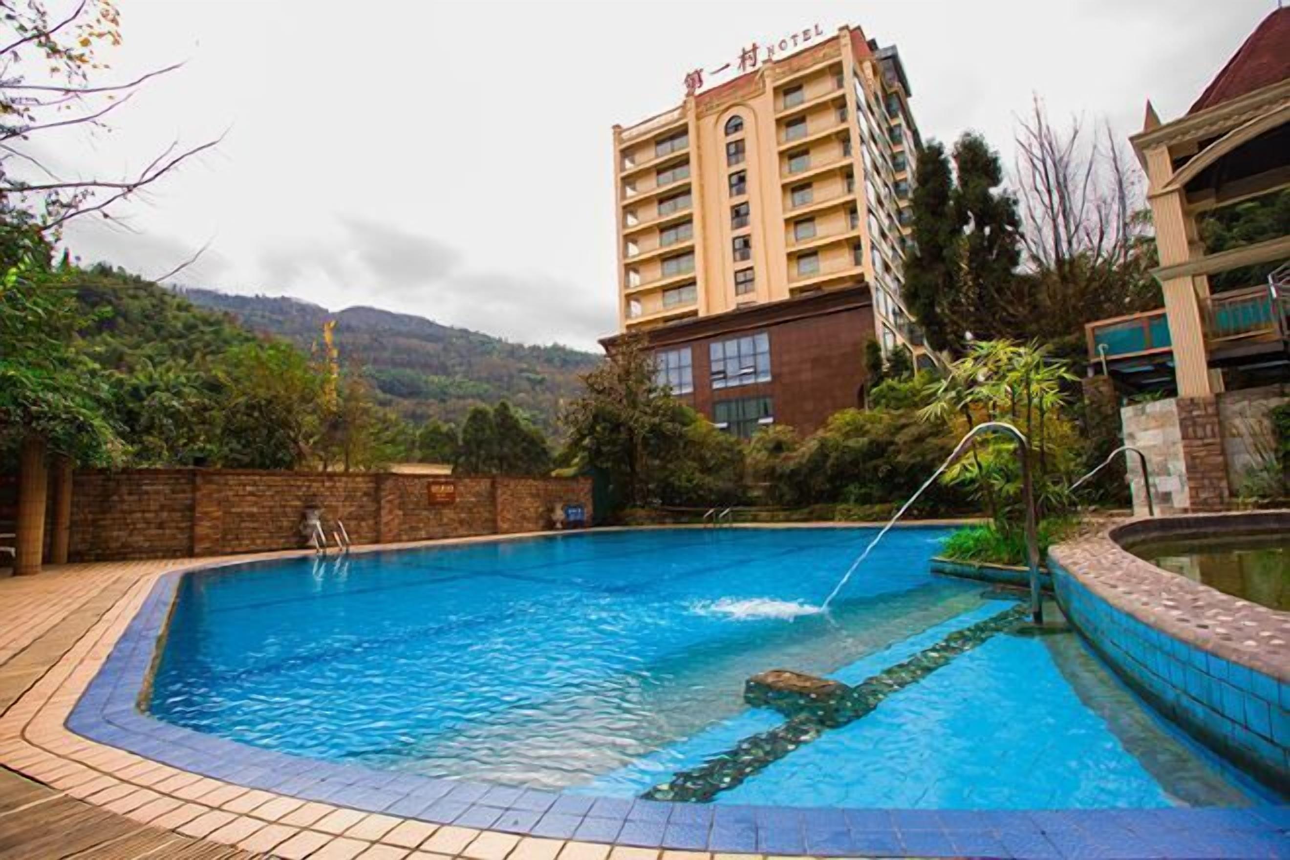 Ein Hotel mit Schwimmbad, umgeben von Grünflächen und Hügeln.