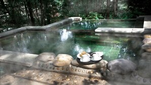 A serene pool area with a stone edge and a table with cups and a plate. - Diyicun Hot Spring Hotel (Dayi)