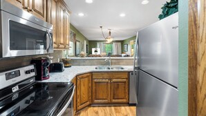 Una cocina moderna con electrodomésticos de acero inoxidable, armarios de madera y encimera de granito.