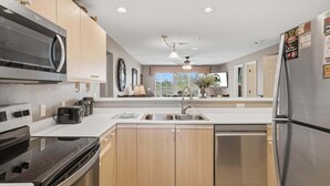 A modern kitchen with a built-in microwave, stove, and dishwasher, wooden cabinets, and a large window providing natural light. - 4 Bedroom, 4 Bathroom Walk-in Golf Condo near Branson Shopping & Entertainment (Branson)