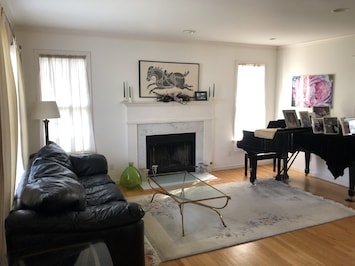 Formal living room with black leather Natuzzi couch and Steinway piano.