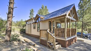 Une cabane dotée d’une terrasse en bois et d’un porche abrité, entourée d’arbres.