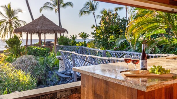 A bar area with a view of a tropical garden and a thatched structure. - Ultra private oceanfront gated compound with pool & spa just minutes from town. (Kailua-Kona)