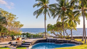 A pool area with a view of the ocean, surrounded by palm trees and a stone wall. - Ultra private oceanfront gated compound with pool & spa just minutes from town. (Kailua-Kona)