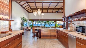 A spacious kitchen with wooden cabinetry, a built-in microwave, and a view of the ocean. - Ultra private oceanfront gated compound with pool & spa just minutes from town. (Kailua-Kona)
