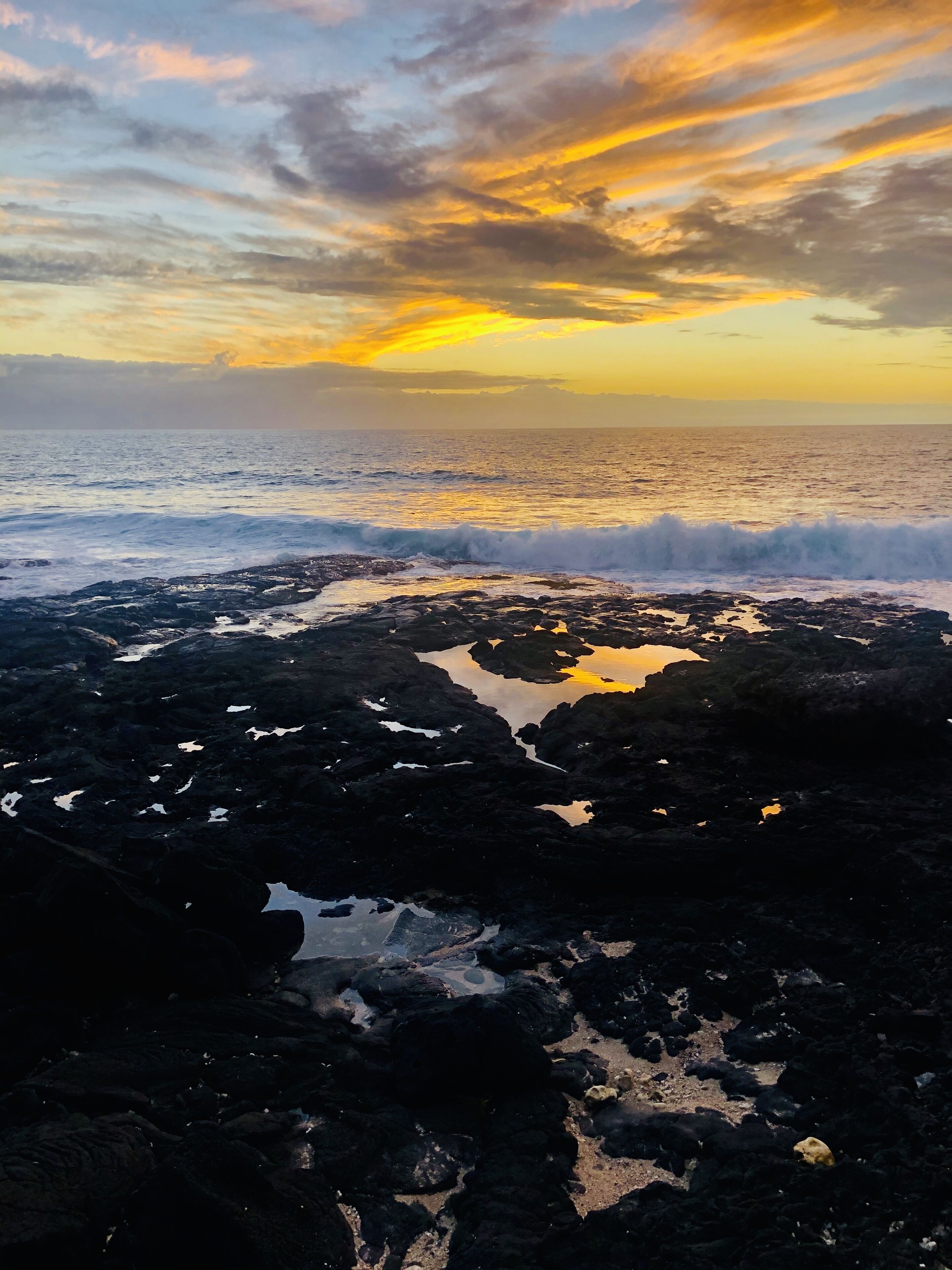 Una costa rocosa con olas rompiendo sobre las rocas durante el atardecer.
