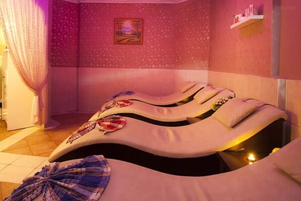 Un cuarto de masoterapia con una camilla curva, un cuadro en la pared y una estantería con objetos.