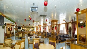 Un restaurante espacioso con varias zonas de estar, incluyendo mesas redondas y cabinas, además de una barra.