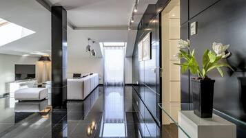 Un moderno vestíbulo de hotel con un mostrador de recepción de vidrio, un sofá y una planta en maceta.