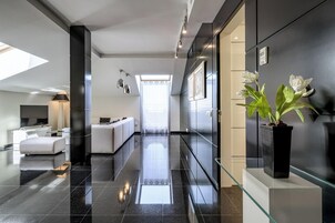 Un moderno vestíbulo de hotel con un mostrador de recepción de vidrio, un sofá y una planta en maceta.