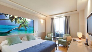 A hotel room with a large bed, two armchairs, a small table, and a TV. - Nelva (Murcia)
