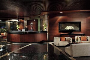 Un vestíbulo de hotel con mostrador de recepción, zona de estar y televisor.