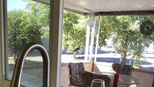 Une cuisine avec un évier, une bouteille de vin et un verre de vin rouge sur une terrasse carrelée.