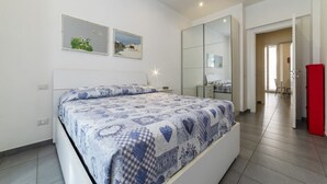 Ein Schlafzimmer mit einem Bett, einem großen Spiegel und einer Tür zu einem Badezimmer.