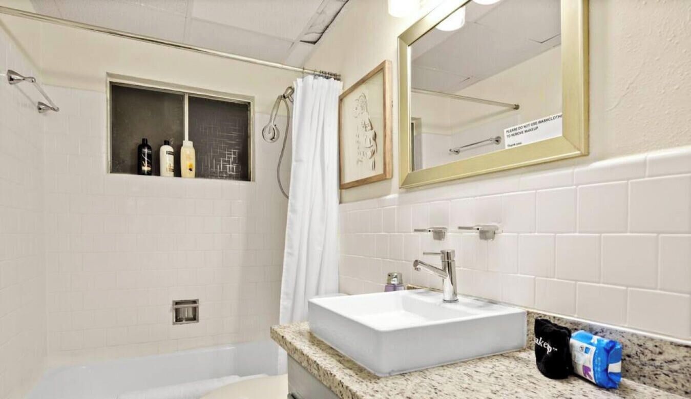Un bagno con lavandino bianco, un water, una doccia e un piccolo ripiano con articoli da toilette.
