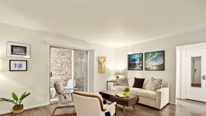 A modern living room with a stone wall, a sofa, a coffee table, and a chair. - Walk to Golf Course! Near Lake + Pool w Parking (Austin)