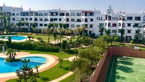 A hotel with multiple white buildings, a swimming pool, and a tennis court.