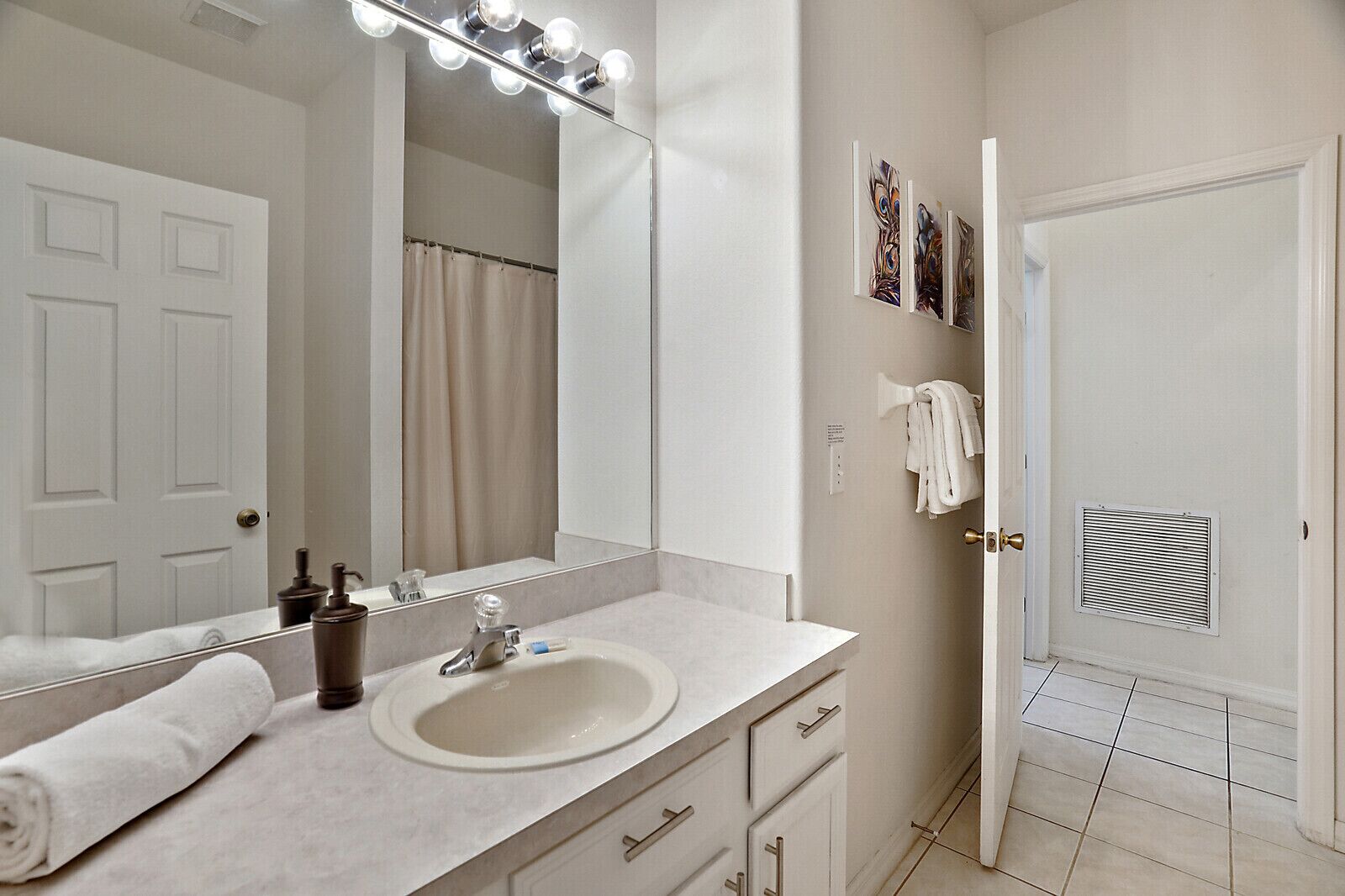 A bathroom with a large mirror, vanity, and a shower curtain.