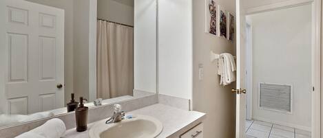 A bathroom with a large mirror, vanity, and a shower curtain.