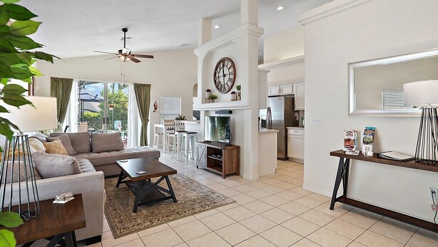A spacious living room with a sofa, coffee table, and a dining area. There is a kitchen with modern appliances and a dining table. - *Disney Pool Home-Heated Pool Included-Clermont FL (Clermont)
