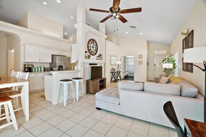 Relax in this inviting living area with a modern kitchen and dining space, featuring a comfortable sofa set, dining table, and kitchen counter with bar stools.