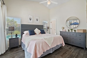 Cozy bedroom with a large bed, dresser, and framed pictures on the wall.