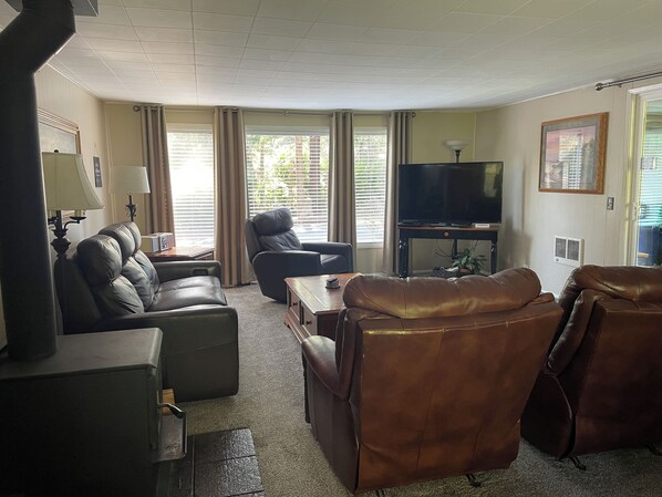 A living room with a sofa, armchairs, a TV, and a fireplace.