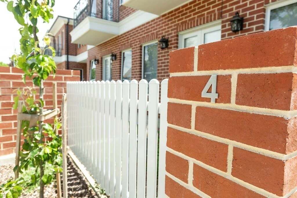 Un edificio in mattoni con una recinzione in legno bianco e il numero 4 sulla parete.