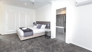 Une chambre à coucher moderne, équipée d’un lit, de lampes de chevet, d’un ventilateur de plafond et d’un espace douche.
