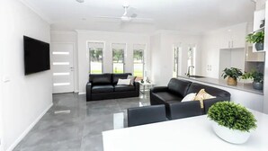 Un salon moderne avec un canapé noir, une table basse blanche et un ventilateur de plafond.