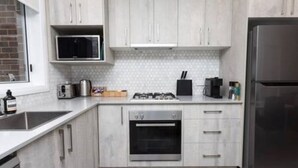 A modern kitchen with a microwave, stove, oven, and refrigerator. - Escape to stylish comfort in this modern apartment! (Wagga Wagga)