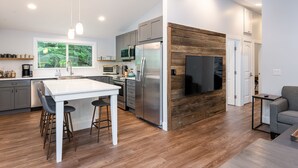 Eine moderne Küche mit einer zentralen Kochinsel, Edelstahlgeräten und einer Wand mit Holzverkleidung.
