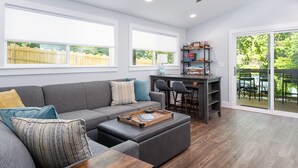 Ein modernes Wohnzimmer mit grauem Sofa, einem Holztisch und einem Deckenventilator.