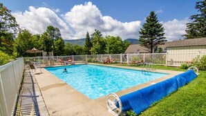 A rectangular swimming pool with a white fence and lounge chairs around it. - Whiffletree D3 (Killington)