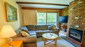 A living room with a sofa, a coffee table, a TV, and a fireplace. - Whiffletree D3 (Killington)