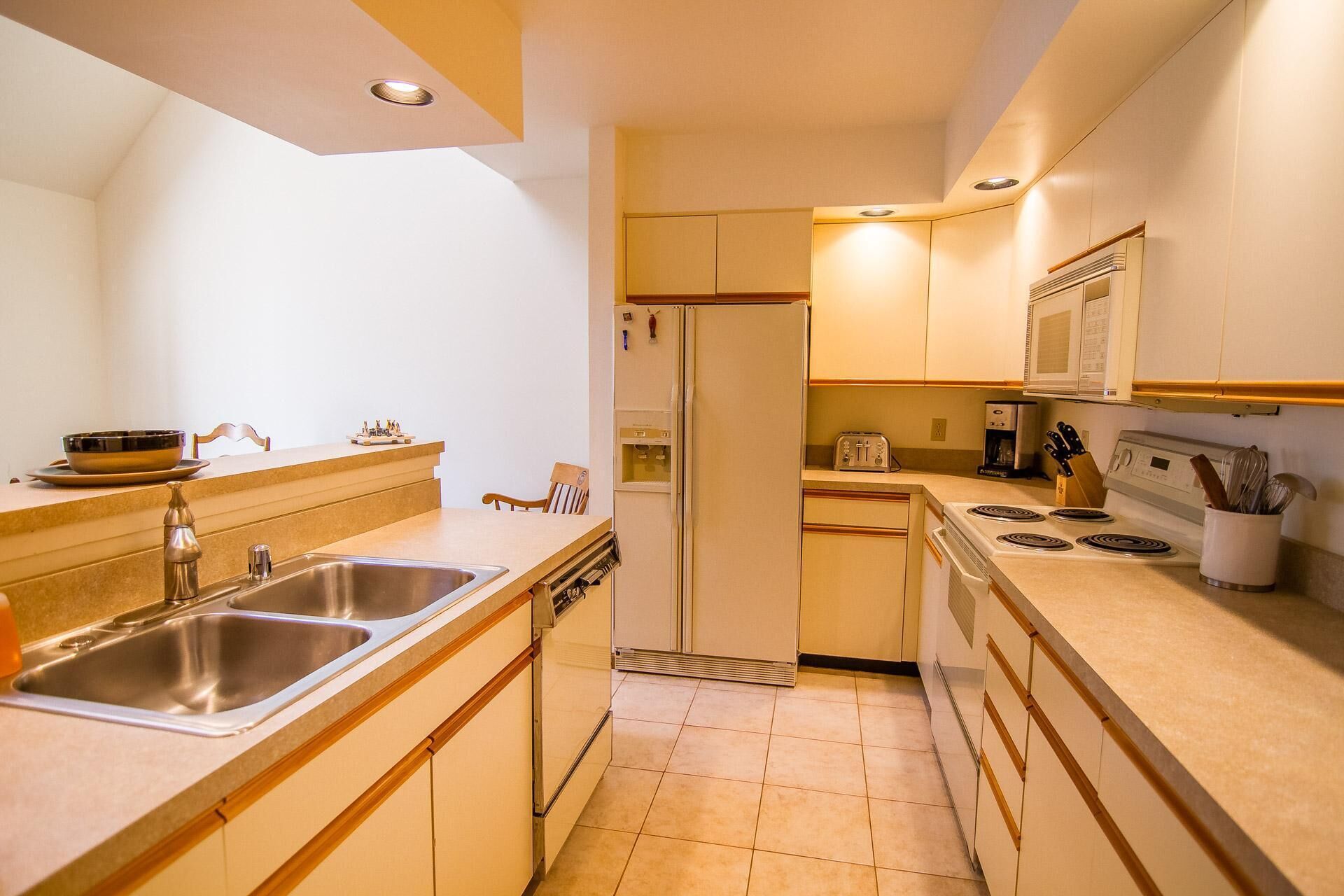 A compact kitchen with a sink, stove, microwave, and refrigerator.