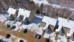 A parking lot with several cars and a building with a sloped roof. - Whiffletree B8 (Killington)