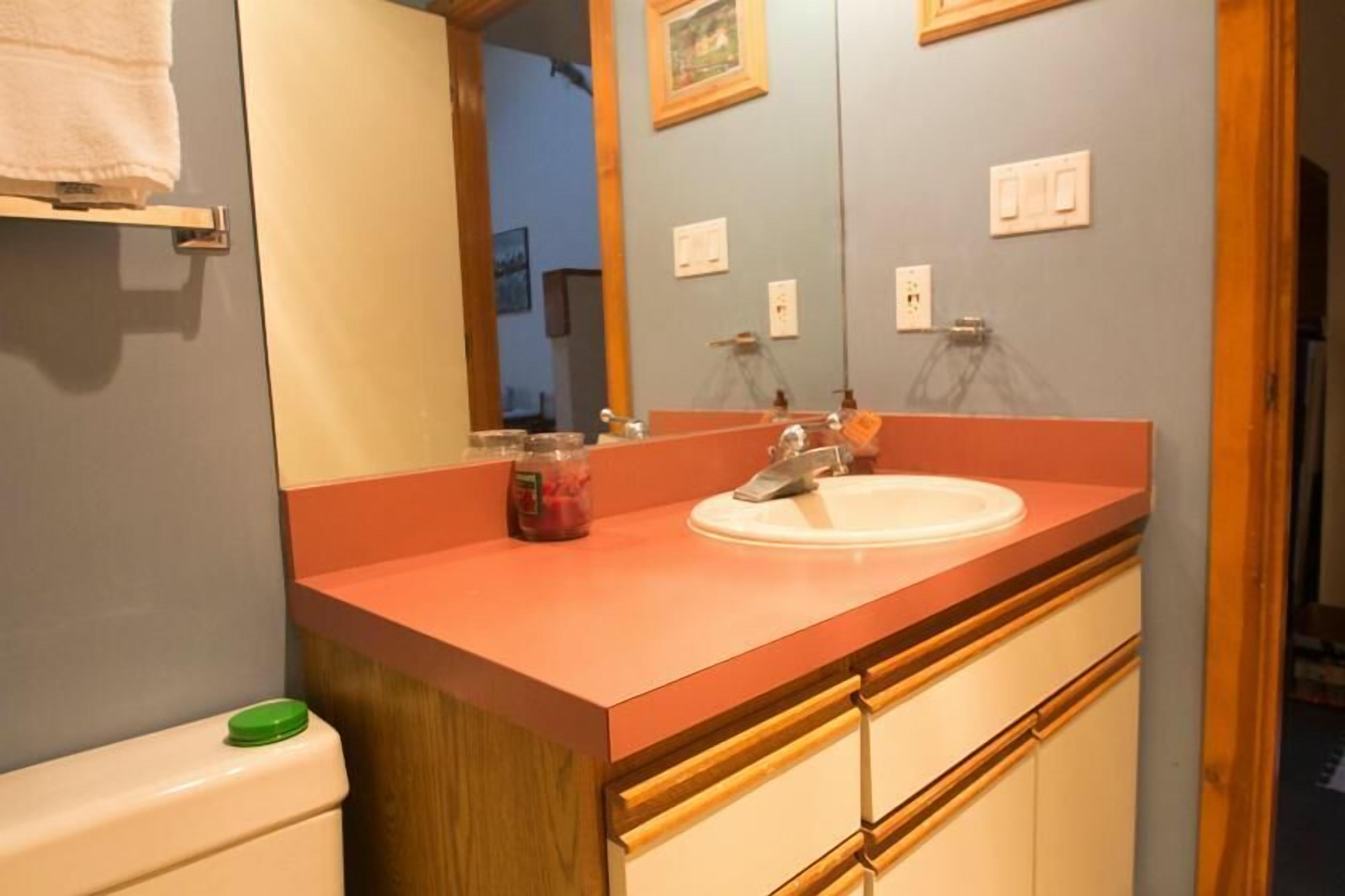A bathroom with a wooden vanity, a white sink, and a mirror above it.