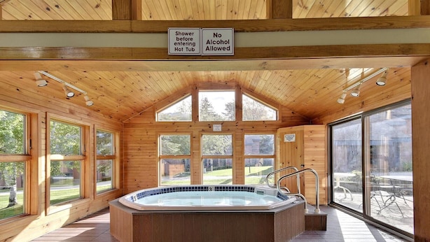 Una cabaña de madera con jacuzzi, ventanas amplias y un letrero que prohíbe el consumo de alcohol.