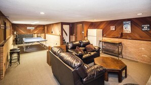 Un espacio interior acogedor con una mesa de billar, un sofá de cuero y una chimenea.