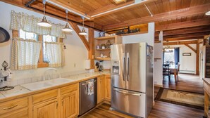 A kitchen with wooden cabinets, a stainless steel refrigerator, and a built-in dishwasher. - Viewmont Chalet (Killington)