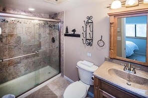 A bathroom with a glass-enclosed shower, a toilet, and a vanity with a sink and mirror. - Pinnacle F8 (Killington)