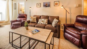 A living room with a brown leather sofa, two leather armchairs, a coffee table, and a floor lamp. - Pinnacle F8 (Killington)