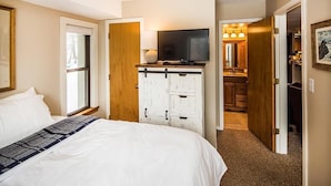 A hotel room with a bed, a television, a dresser, and a bathroom visible through an open door. - Pinnacle F8 (Killington)