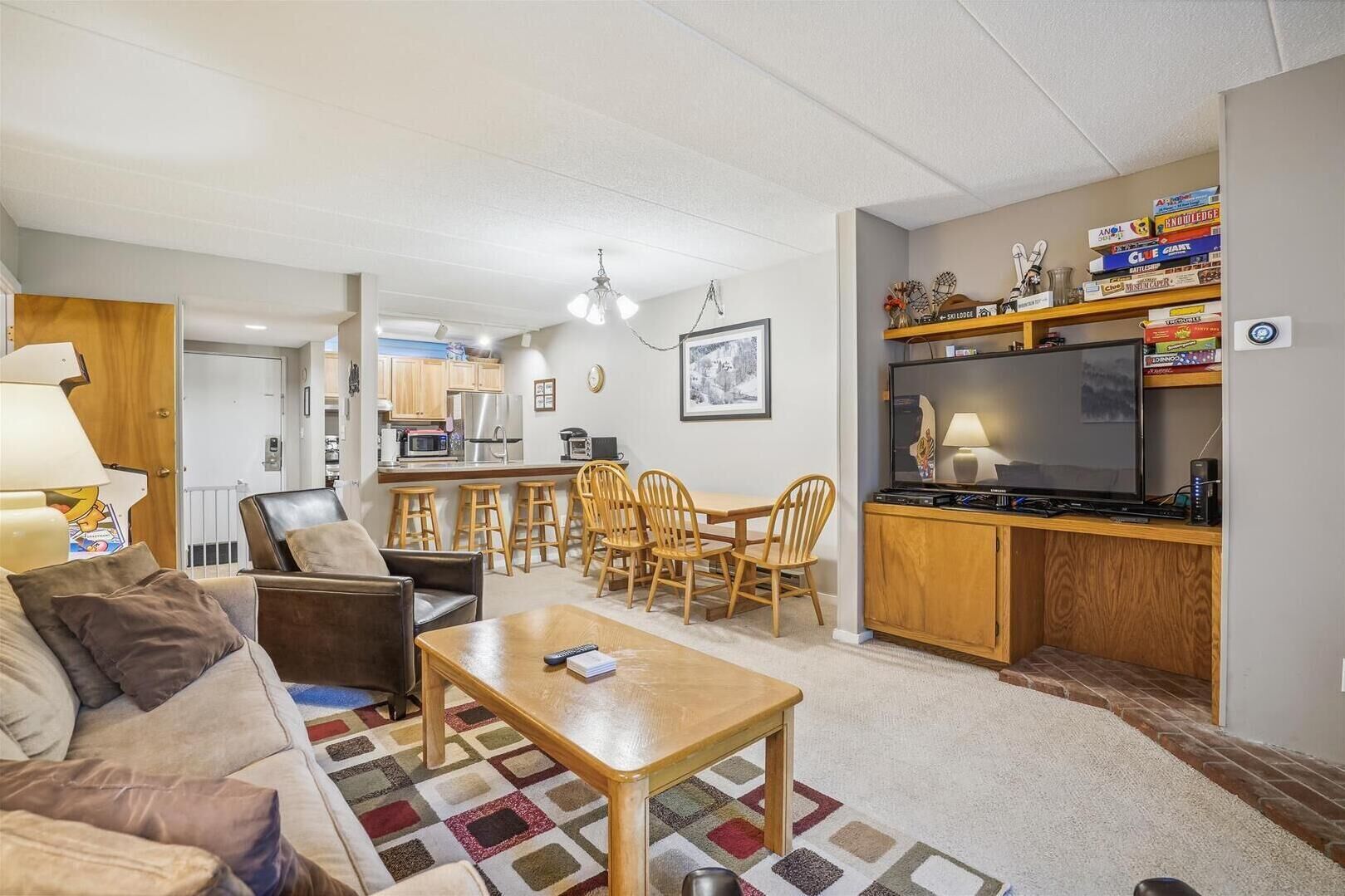 En kompakt bolig med tekøkken, spiseplads og opholdsområde med sofa og stole.