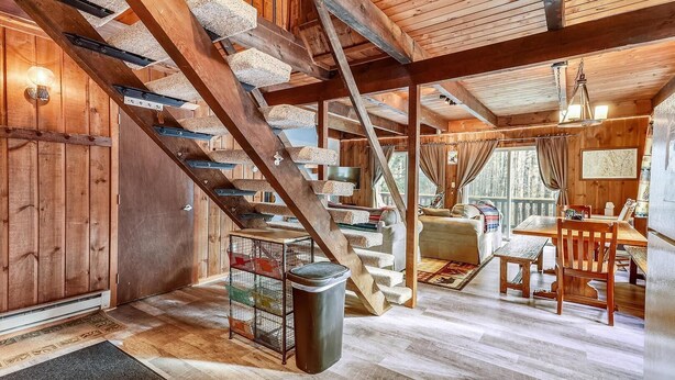 A rustic cabin interior with a wooden staircase, a dining area, and a cozy living space. - Hemlock Ridge 1D (Killington)